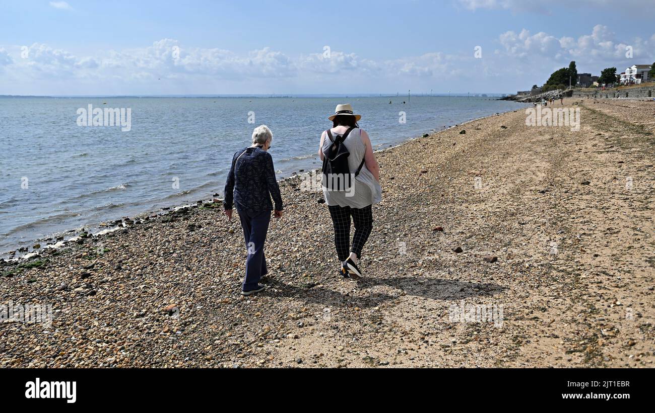 Shoeburyness. Regno Unito. 27 agosto 2022. Due donne camminano lungo la ciottola a Shoeburyness East Beach, Essex, Regno Unito Foto Stock