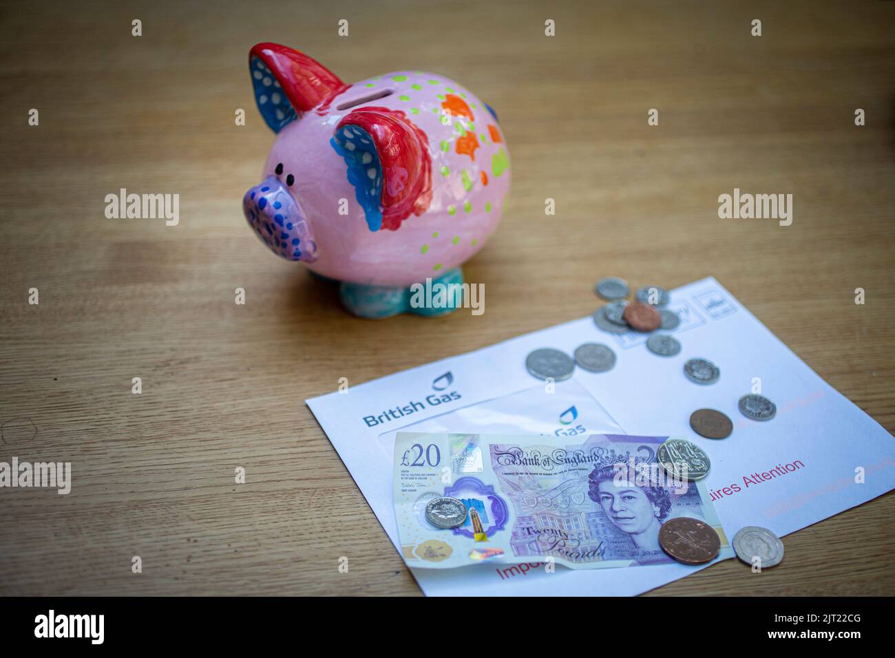 Piggy bank con bolletta del gas, banconote inglesi £20 e monete come razzo bollette del carburante Foto Stock