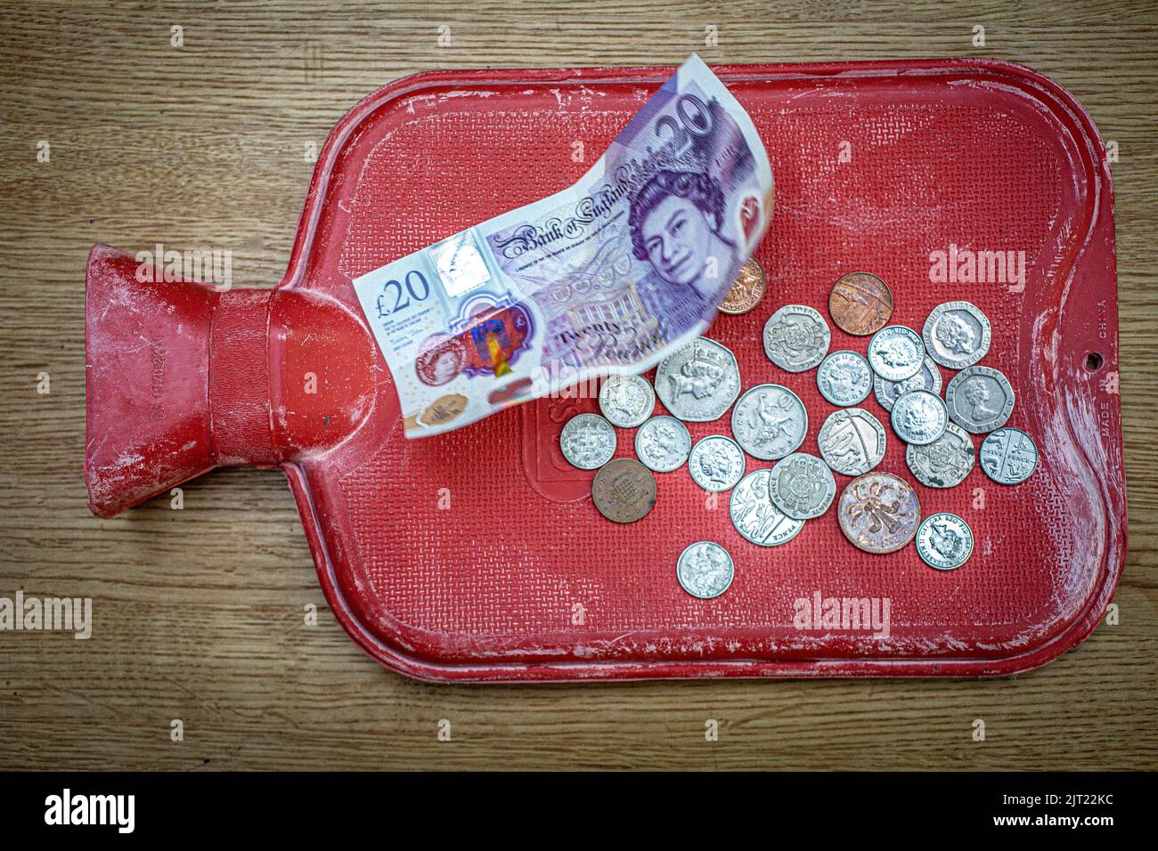 Primo piano di una bottiglia di acqua calda e British £20 banconote e monete come carburante bollette razzo Foto Stock