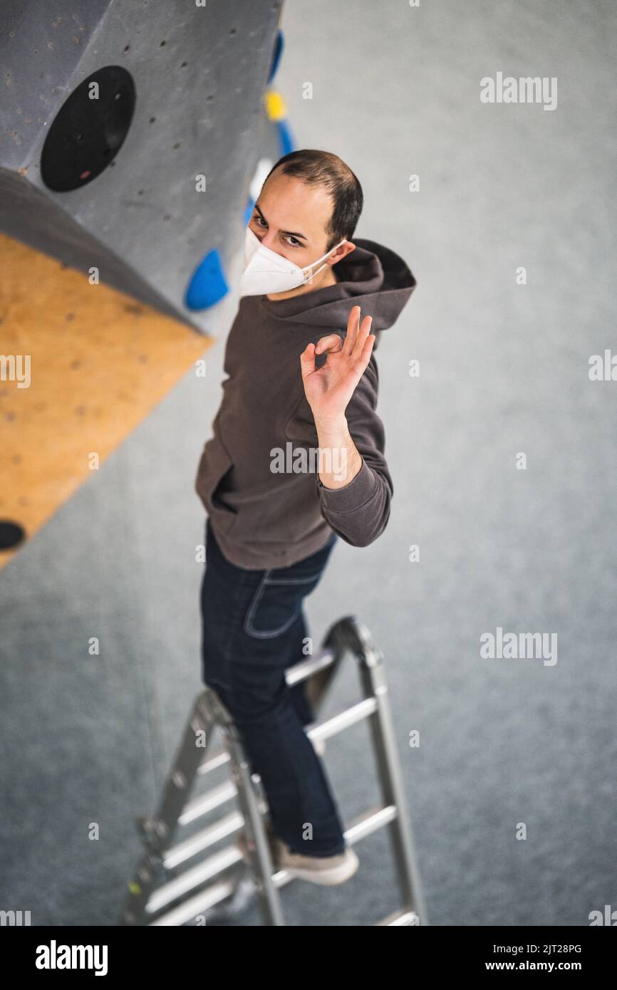 Un apparecchio di arrampicata che cerca di impostare un percorso nella palestra bouldering Foto Stock