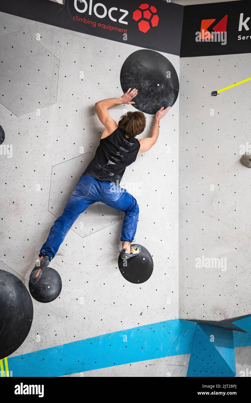 Un atleta forte che si arrampica sul muro nella palestra bouldering di Boulderwelt Foto Stock
