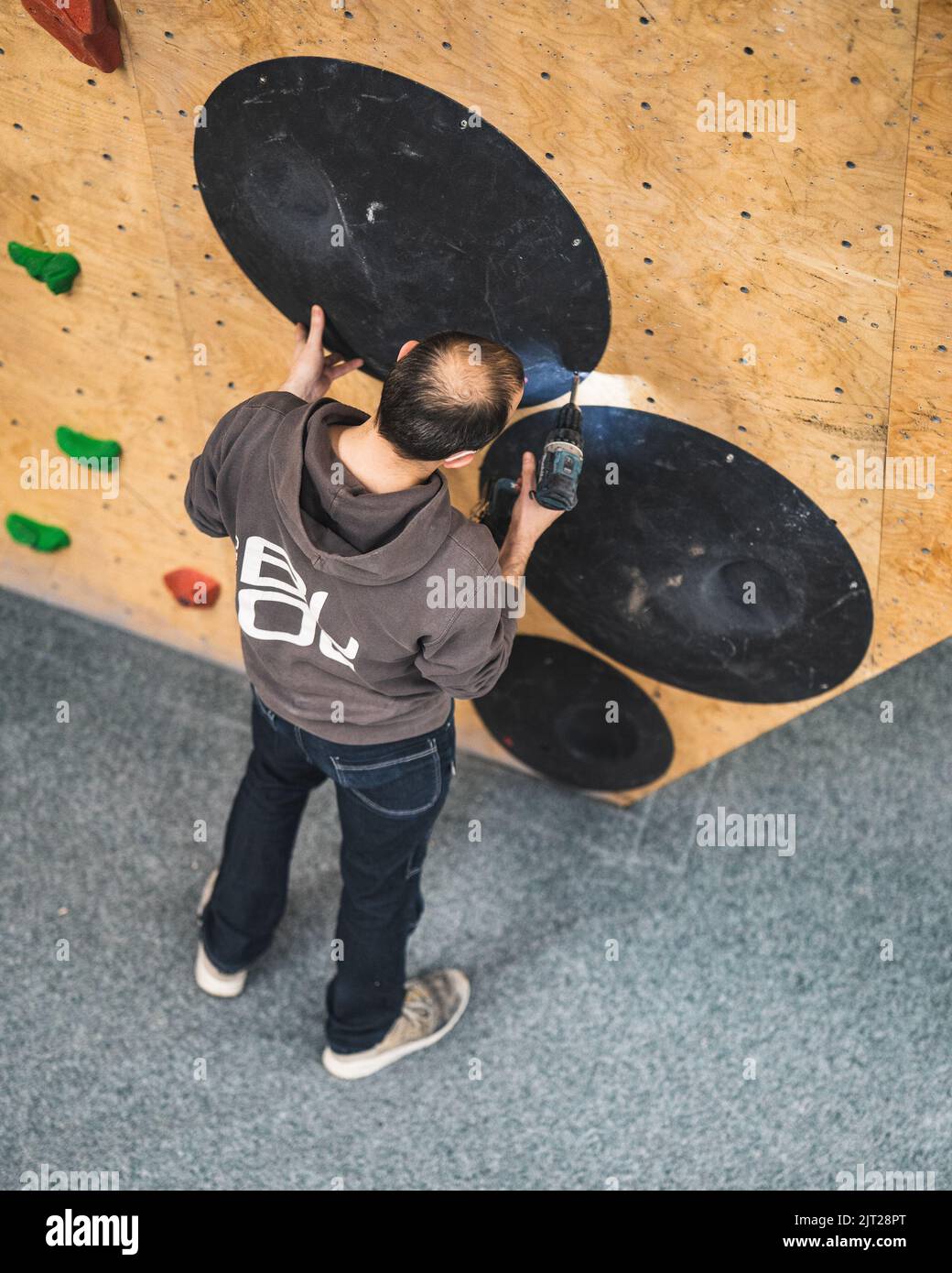 Un apparecchio di arrampicata che cerca di impostare un percorso nella palestra bouldering Foto Stock