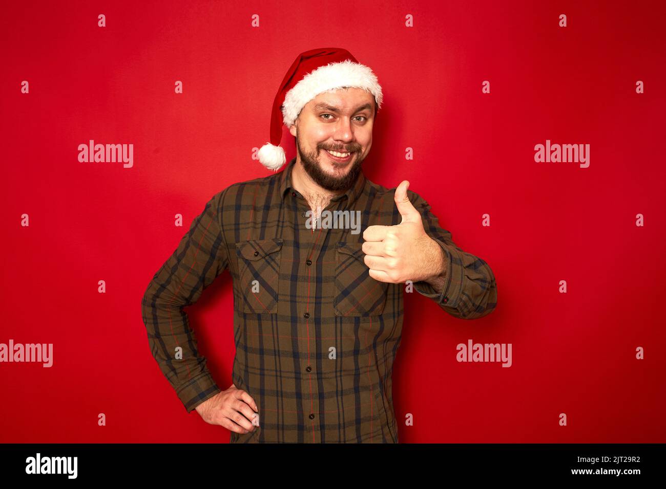 Sorridente uomo a Natale babbo natale cappello casual abiti mostra pollici in avanti raccomanda approva Foto Stock