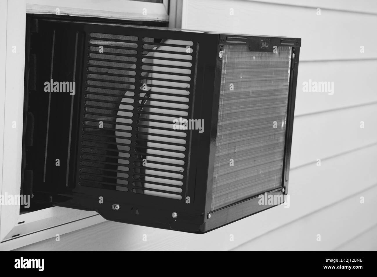 Nuova unità finestrino A/C installata su una casa singola per riscaldare e raffreddare casa in bianco e nero Foto Stock