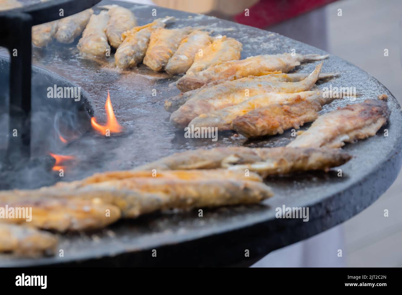 Pesce europeo puzzato croccante su braciere nero all'aperto mercato alimentare Foto Stock