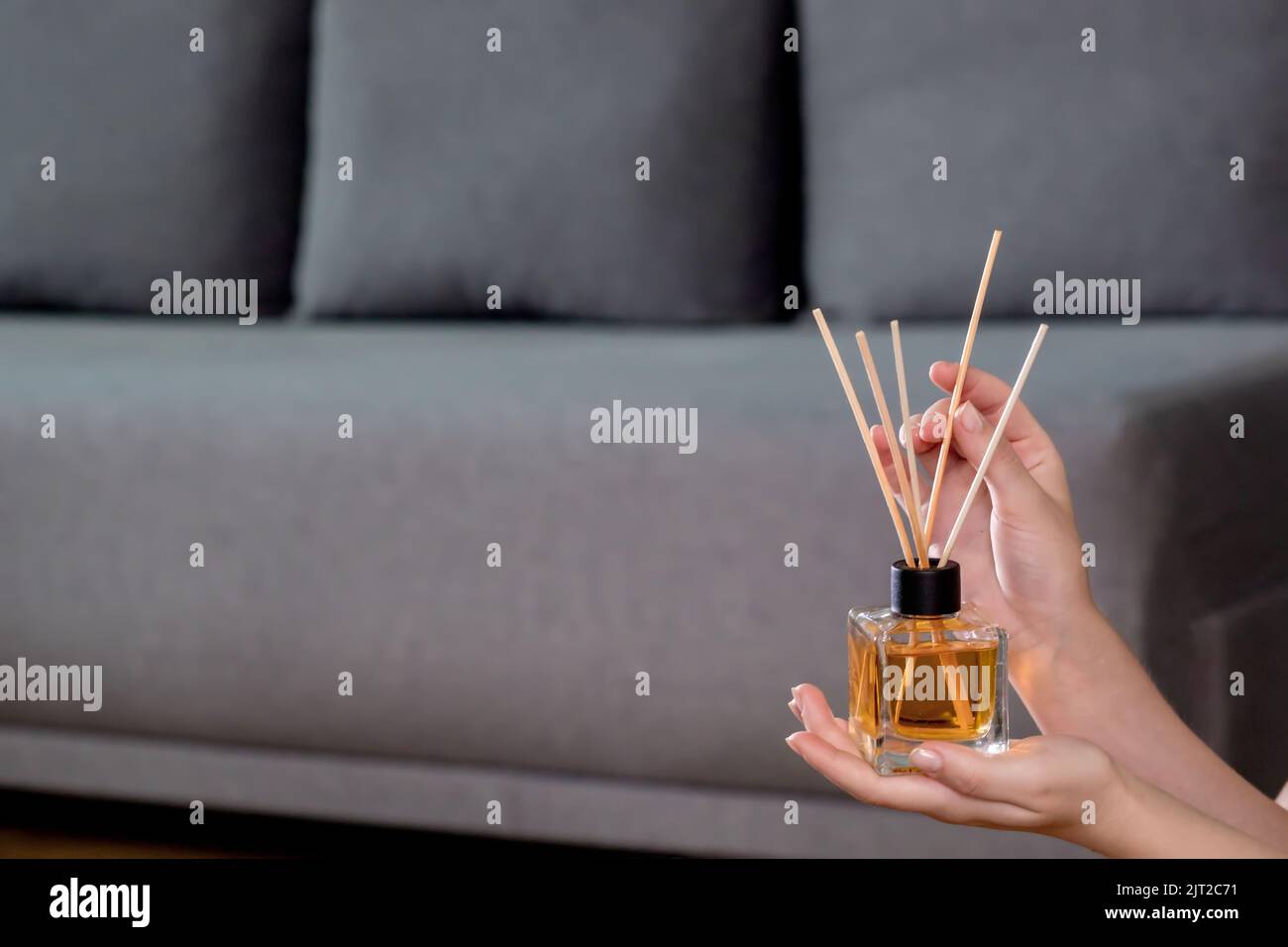 Profumatore per aria di canna aromatica donna che tiene in mano sullo sfondo della stanza. Diffusore di aroma. Deodorante per ambienti domestici Foto Stock