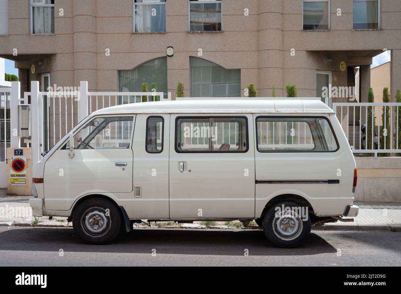 Una vista laterale di primo piano di un vecchio furgone bianco Nissan Vanette parcheggiato sulla strada di fronte ad un edificio Foto Stock