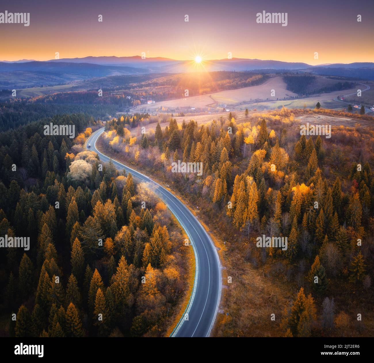 Vista aerea della strada di montagna nella foresta arancione al tramonto Foto Stock