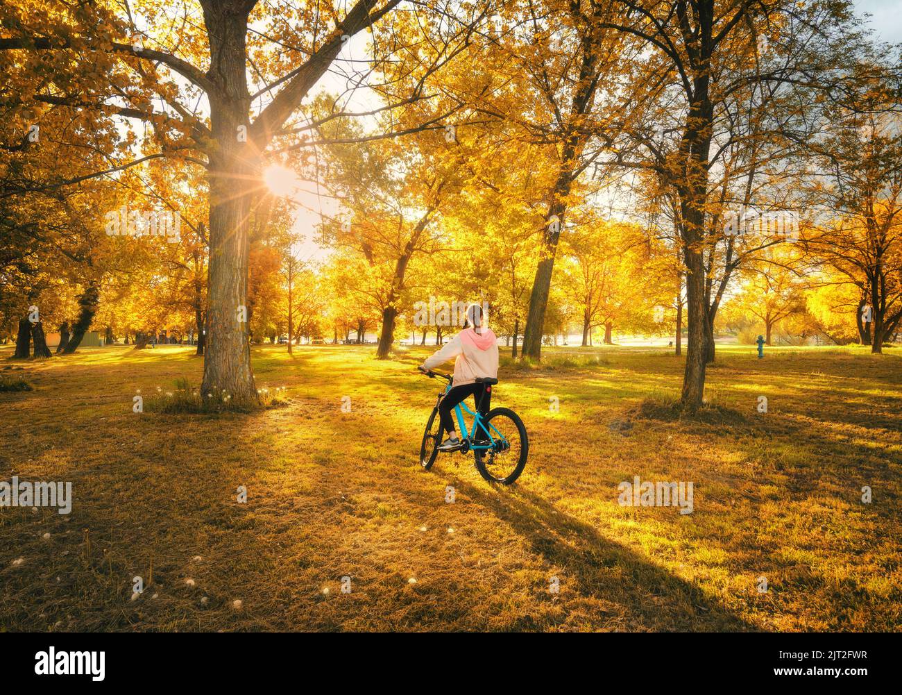 Donna in mountain bike e aranci al tramonto in autunno Foto Stock