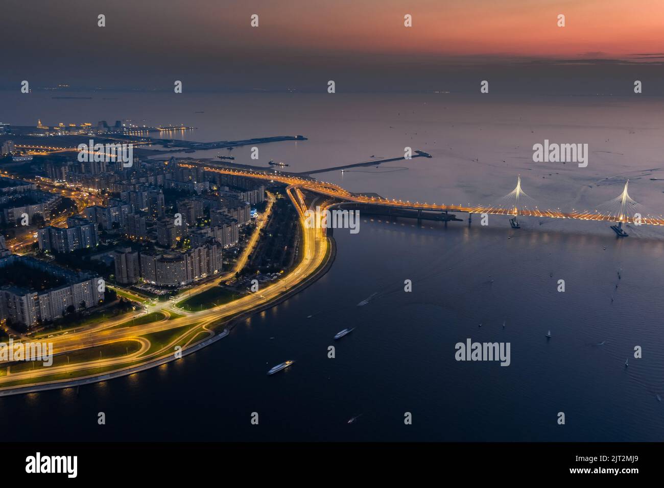 Un tramonto pittoresco sul ponte sterrato e sull'isola di Vasilevsky, porto marittimo passeggeri, autostrada illuminata Foto Stock