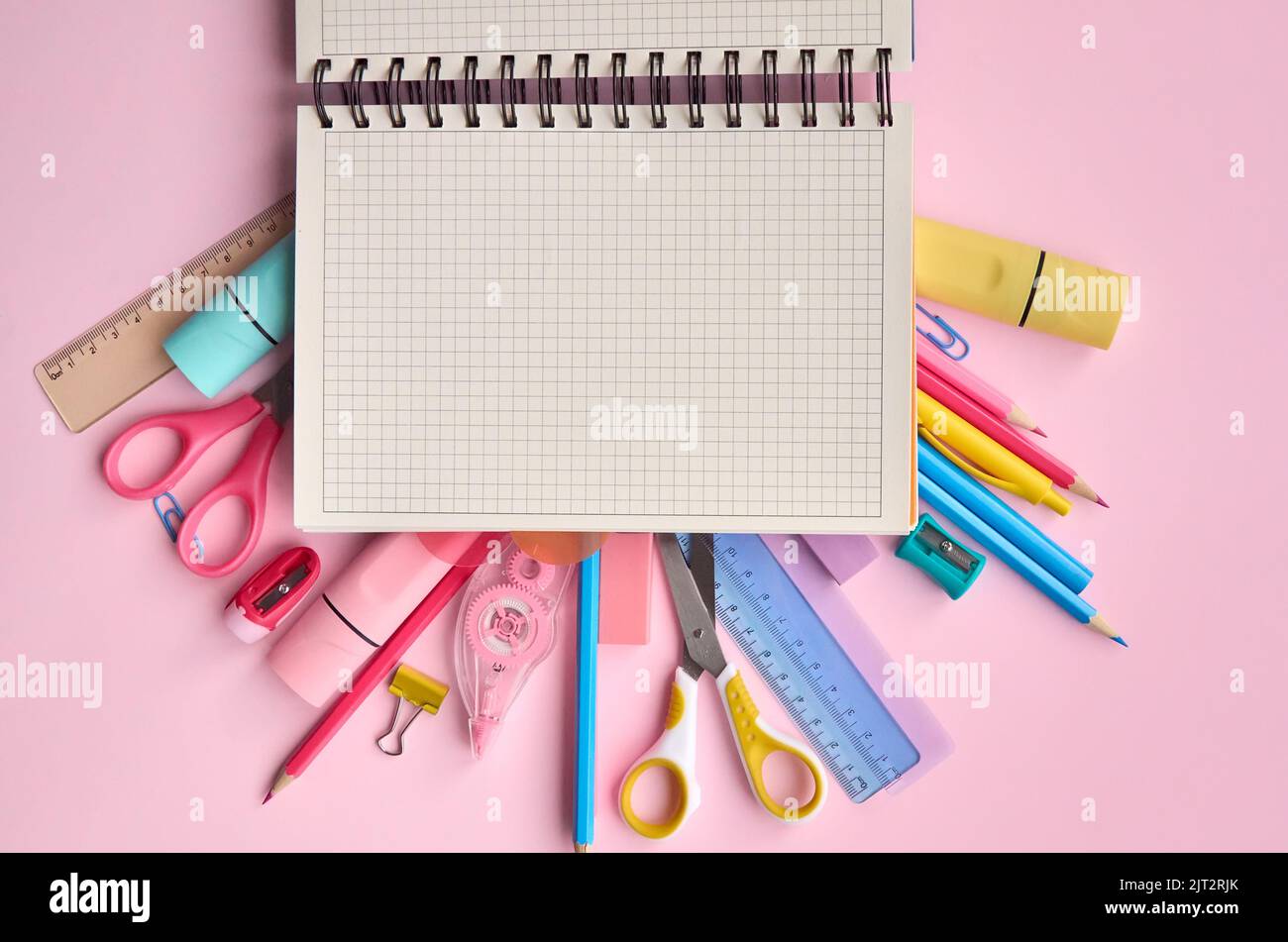Il notebook aperto e la scuola fornisce gli accessori dei prodotti su sfondo pastello. Foto Stock