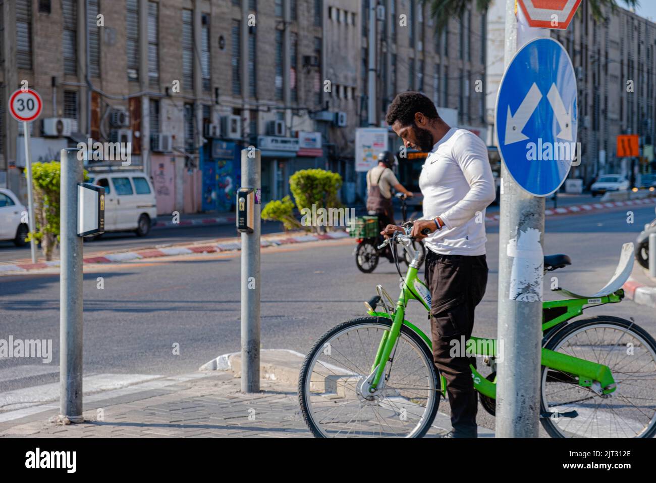 L'uomo nero va in bicicletta verde nella città di Tel Aviv. Foto Stock