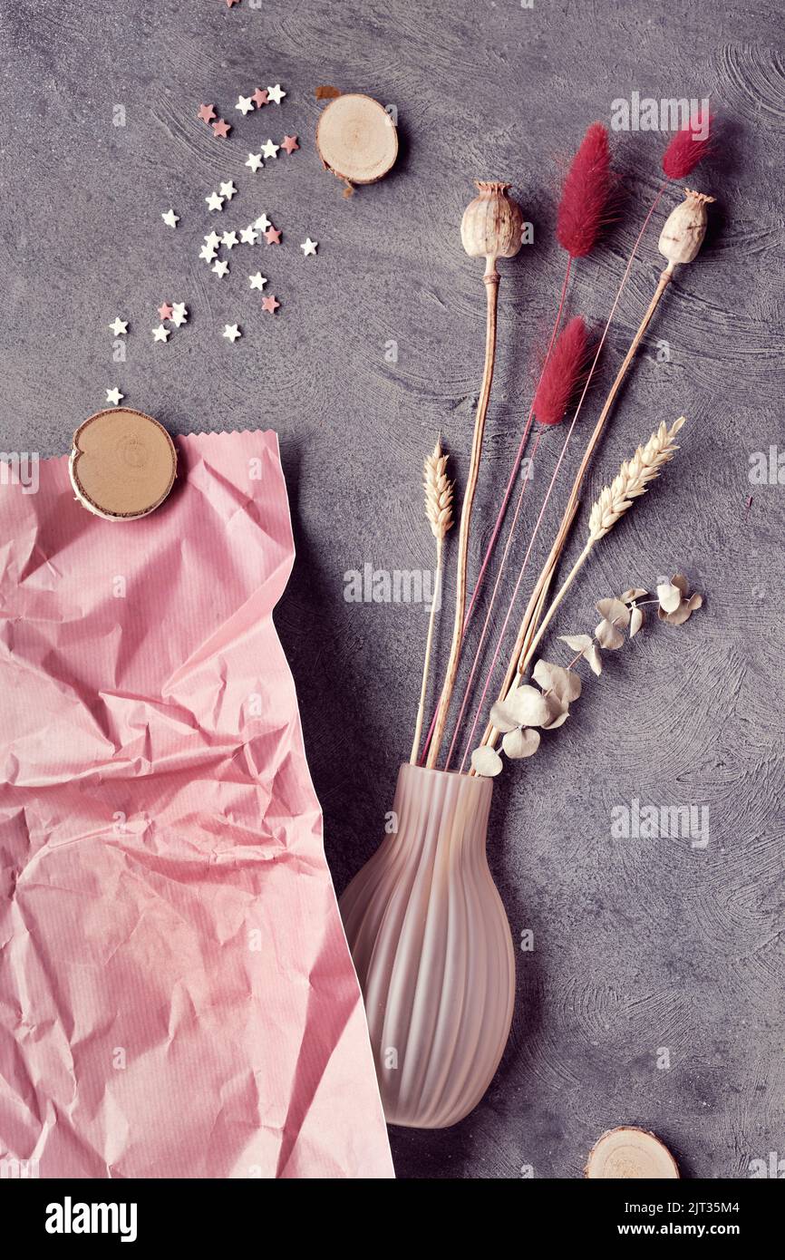 Fondo autunnale con vaso di vetro rosa a secco. Piante di coda di papavero e coniglietto con cerchi di legno. Vista dall'alto, disposizione piatta su sfondo scuro Foto Stock