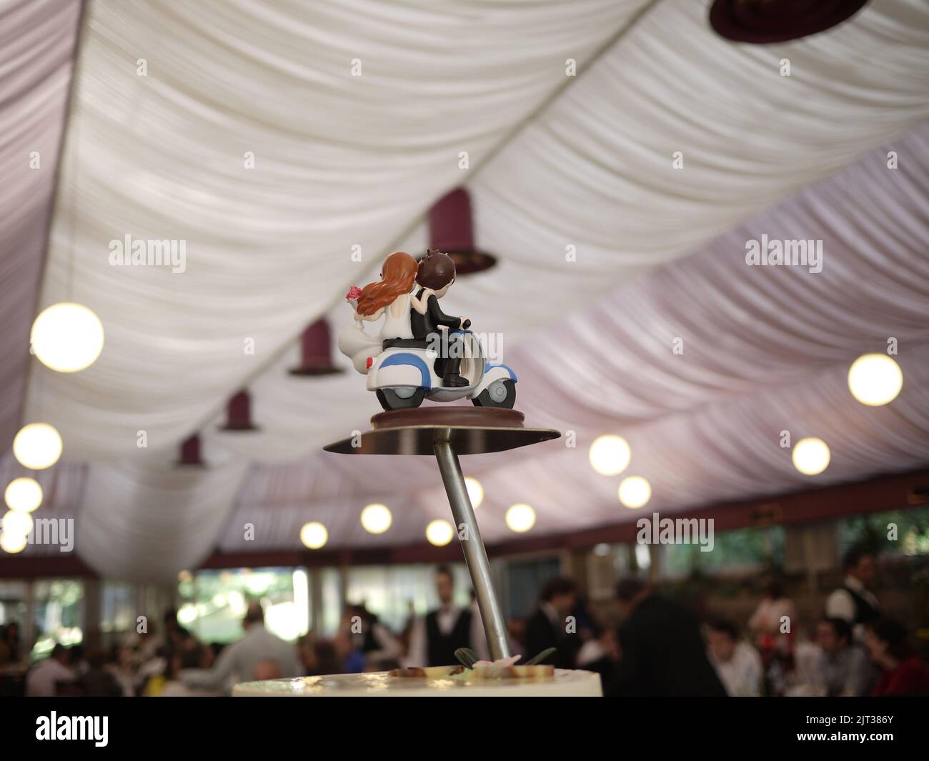 Una torta nuziale con figure della sposa e dello sposo su uno scooter Foto Stock