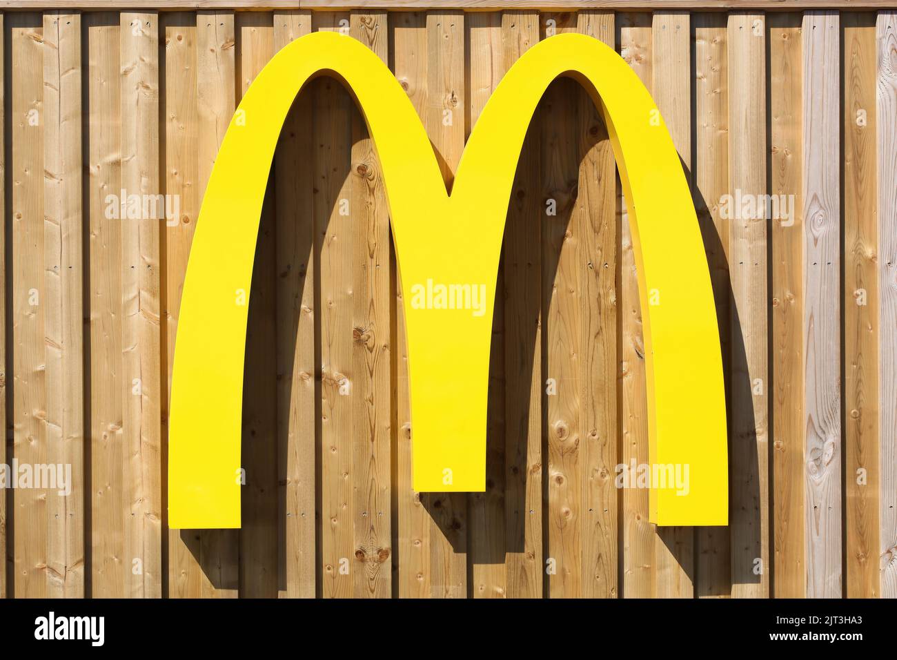 Aarhus, Danimarca - 14 aprile 2022: Il logo di McDonald's su una facciata a strisce. McDonald's è la più grande catena di fast food al mondo Foto Stock