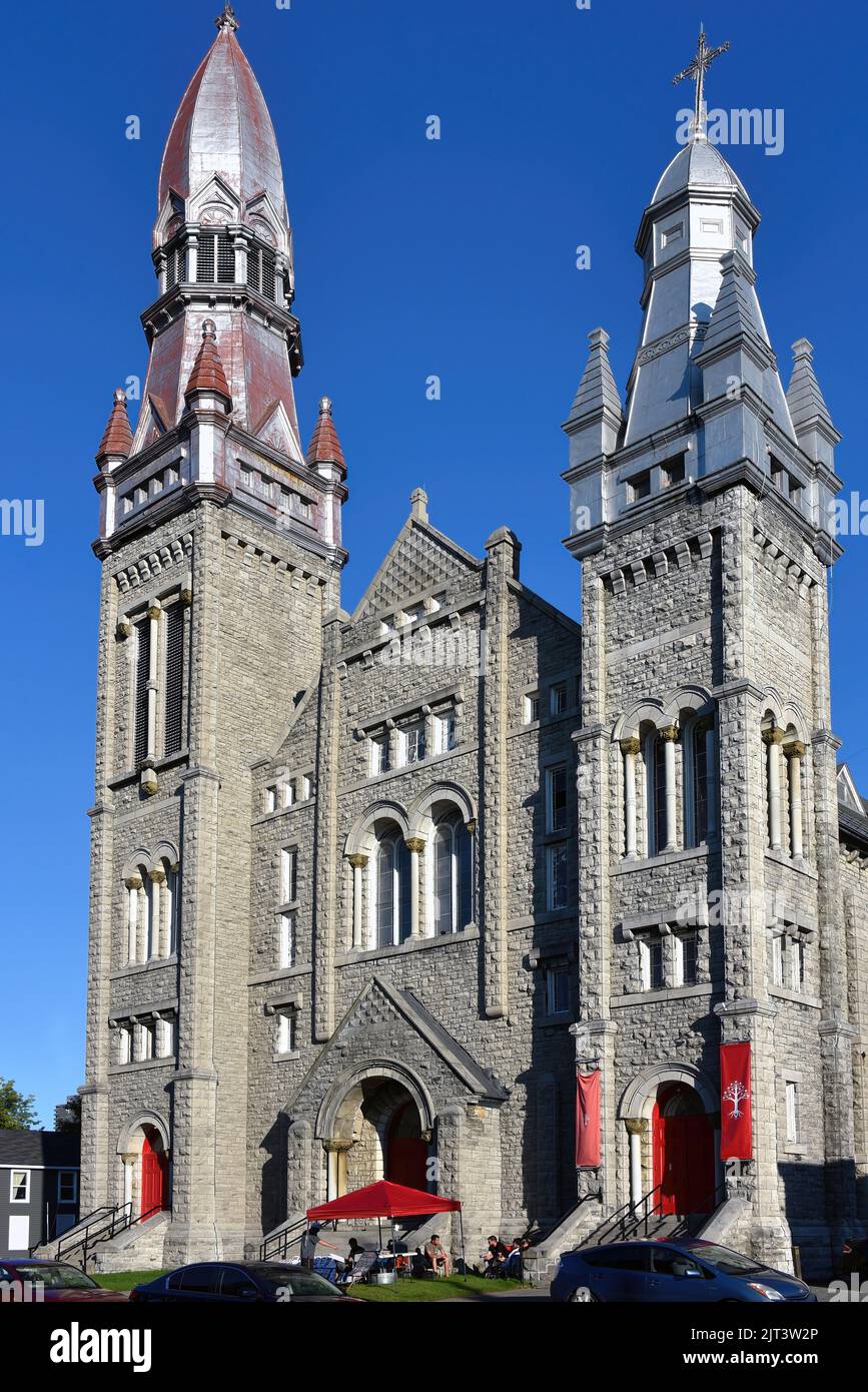Ottawa, Canada - 20 agosto 2022: Un gruppo chiamato il popolo Unito del Canada, con legami con il convoglio di camion che paralizzò gran parte del centro di Ottawa all'inizio dell'anno, sta affittando l'edificio Heritage St. Brigida's Church come loro ambasciata. Sono stati recentemente serviti un avviso di sfratto, ma continuano a rifiutarsi di andarsene. I loro striscioni sono in mostra sulla chiesa così come le porte rosse recentemente dipinte. Foto Stock
