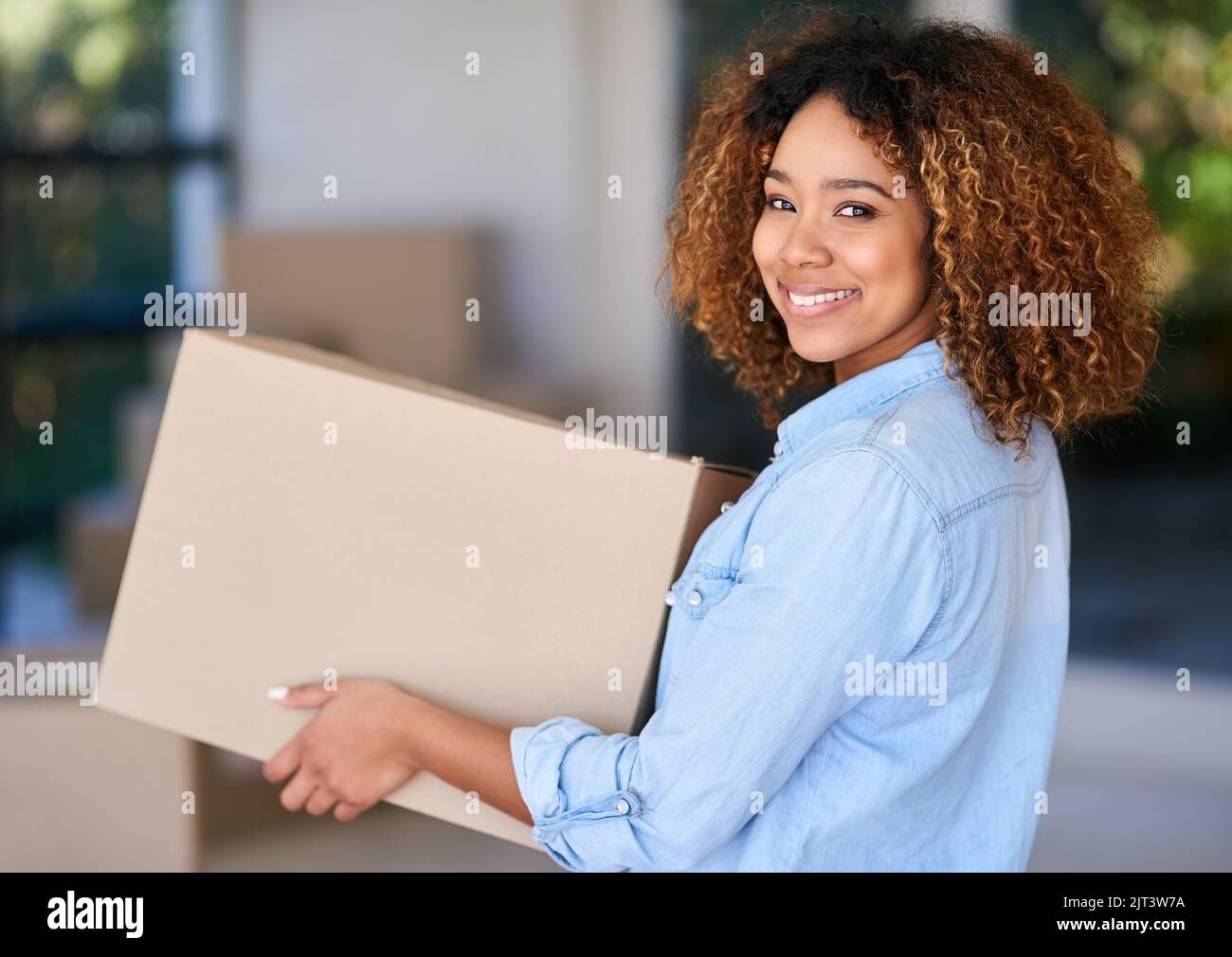 Nuovi inizi sono sempre emozionanti. Ritratto di una giovane donna che porta una scatola di cartone nella sua nuova casa. Foto Stock