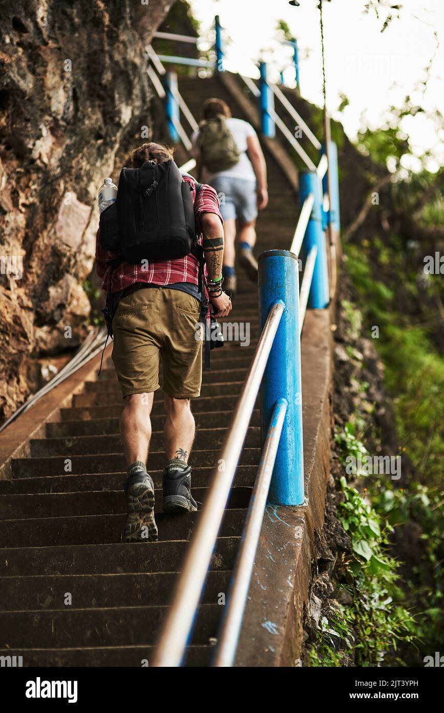 Prendere il sentiero insieme. Ripresa da dietro di due uomini che salpano le scale mentre camminano in montagna. Foto Stock