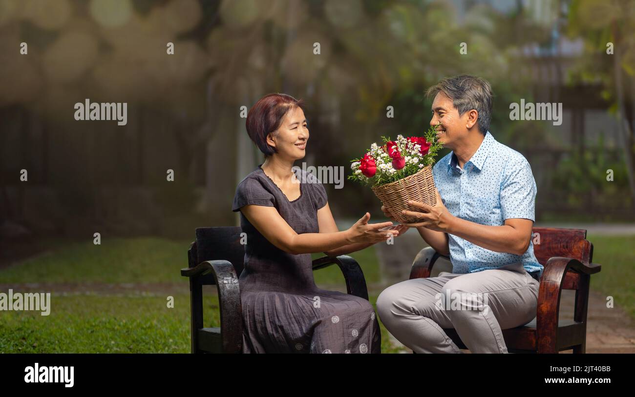 L'uomo anziano asiatico dà una rosa a sua moglie nel giorno dell'anniversario di matrimonio. Foto Stock