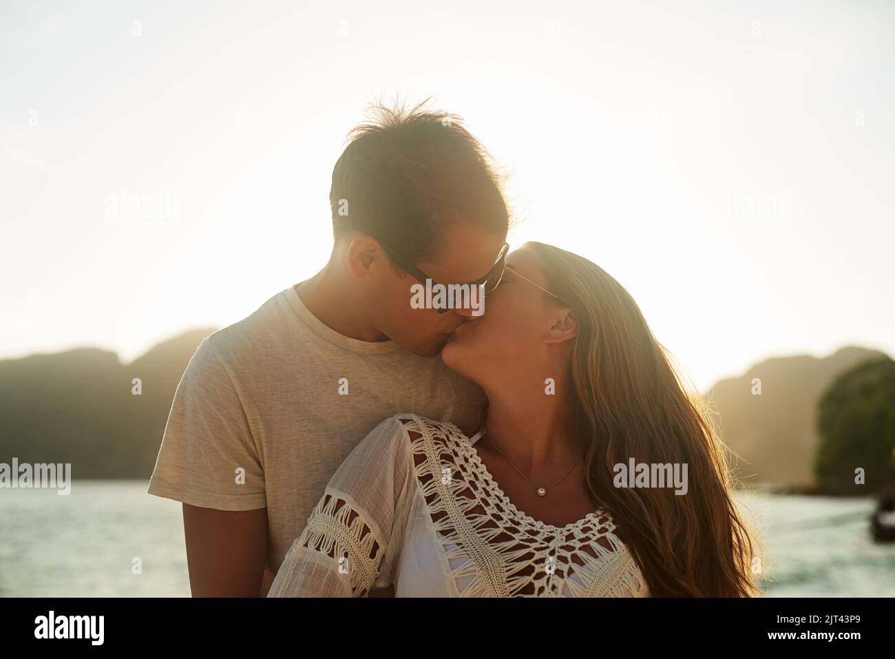 Bacia al tramonto, una giovane coppia affettuosa sulla spiaggia al tramonto. Foto Stock