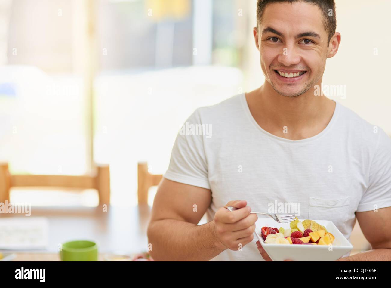 Mangiate un pasto a base di frutta a colazione, un giovane che mangia un'insalata di frutta. Foto Stock