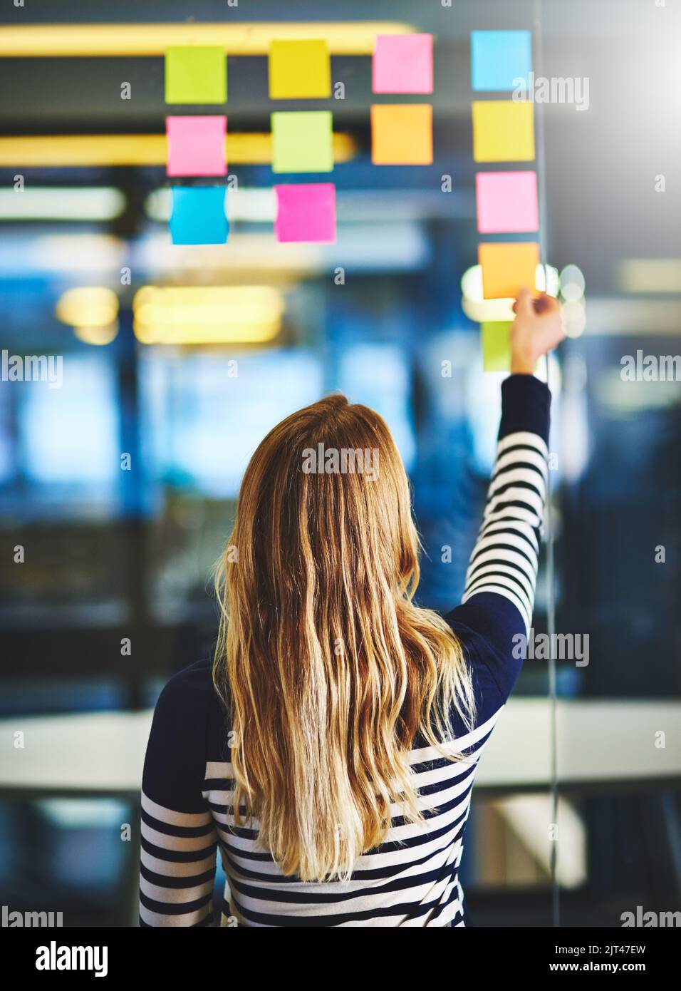 Nessuna idea viene lasciata alle spalle. Ripresa da dietro di una donna che ha una sessione di brainstorming con note appiccicose al lavoro. Foto Stock
