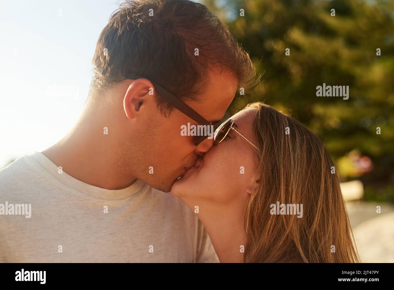 Si bacia sulla costa, una giovane coppia affettuosa sulla spiaggia al tramonto. Foto Stock
