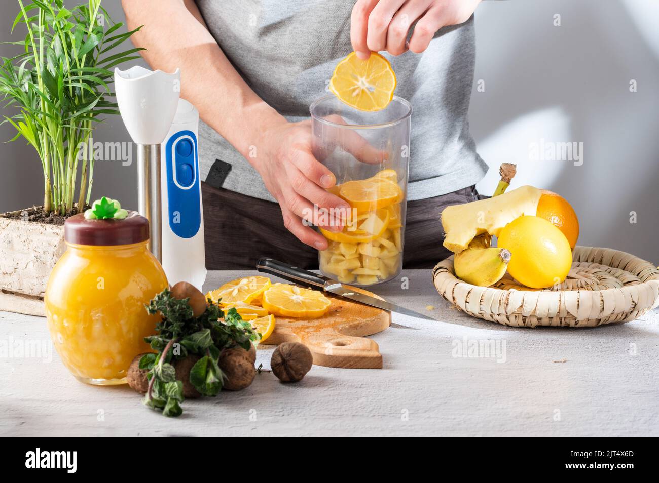 Aggiungere una fetta di arancia al bicchiere del frullatore. Preparazione di cocktail di frutta. Noci e miele. Menta e miele. Foto Stock