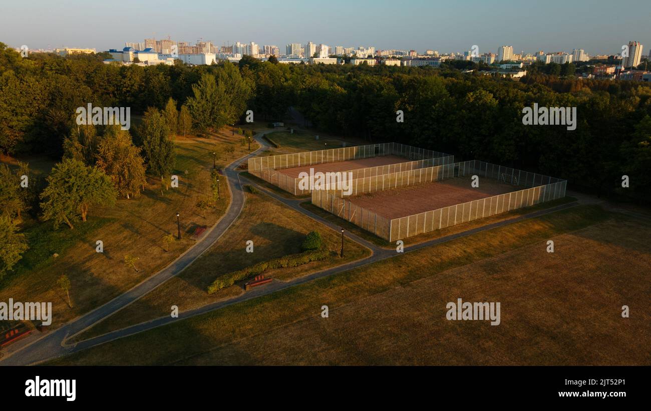 Campi sportivi nel parco cittadino. Con una recinzione di maglia. Parco cittadino all'alba. Fotografia aerea. Foto Stock