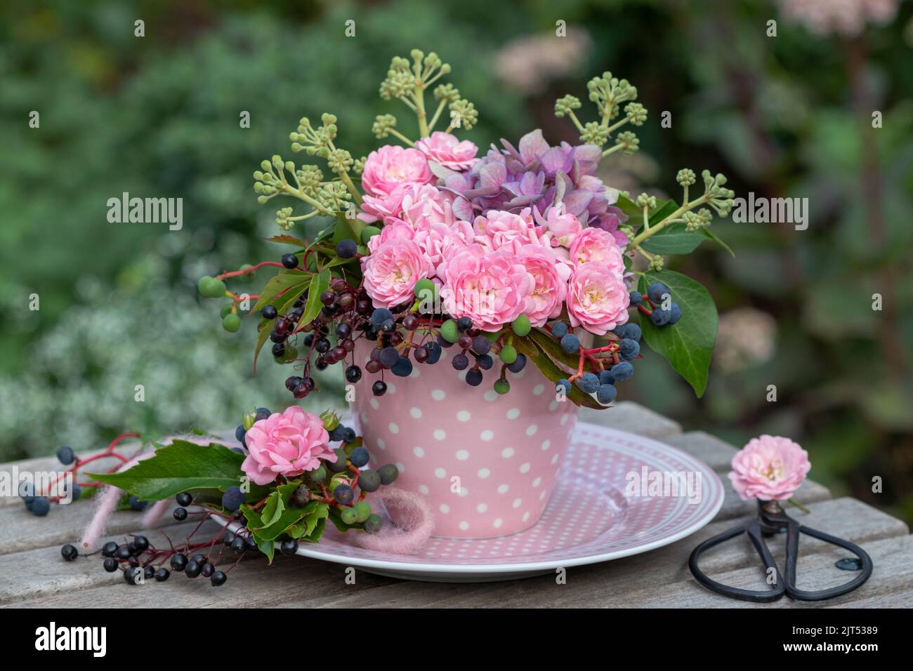 bouquet di rose rosa, fiori di ortensia, bacche di sambuco, bacche di vino selvatico e edera fruttata in tazza Foto Stock