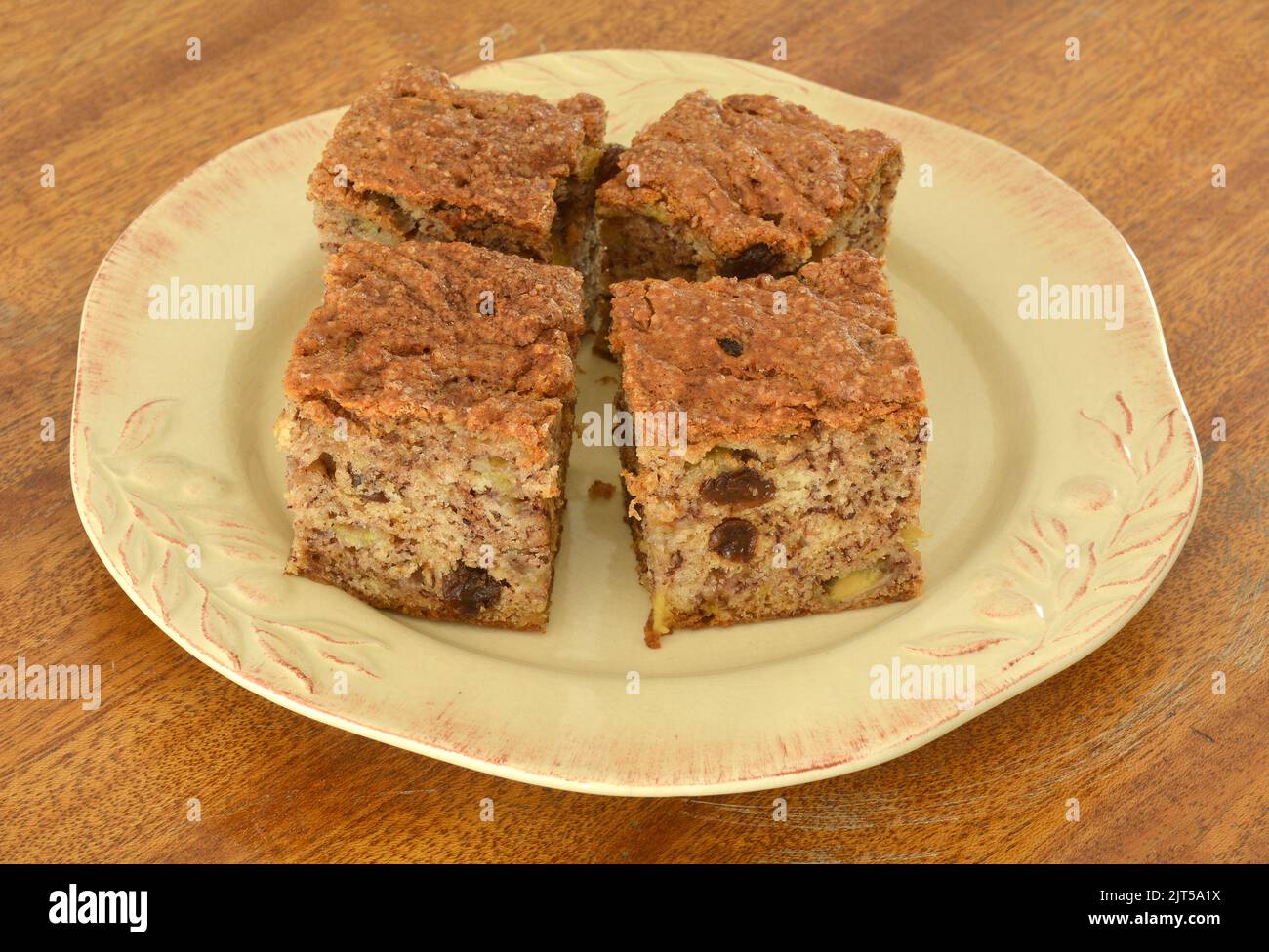 Pane di banana appena sfornato con uvetta e farcitura di zucchero alla cannella. Su piatto rustico giallo e vecchio sfondo di legno afflitto. Formato orizzontale. Foto Stock