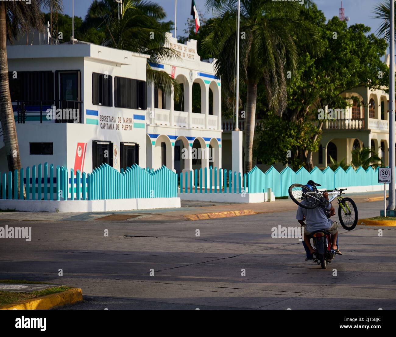 Persone in moto che trasportano una bicicletta in città Foto Stock