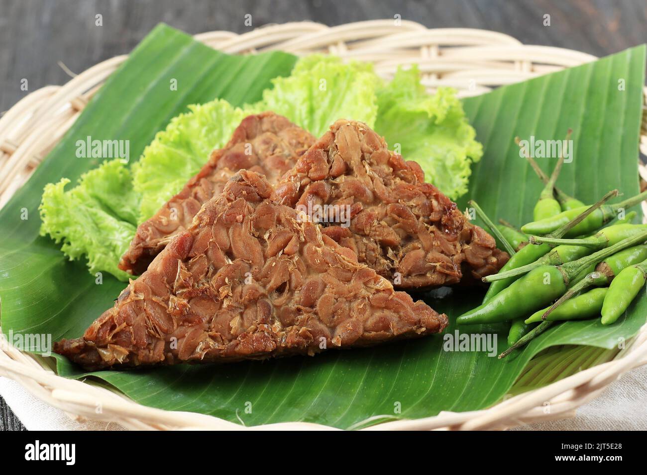 Primo piano Tempe Bacem a forma di triangolo. Tempeh cibo indonesiano bollito con zucchero di palma, servito con peperoncino verde Foto Stock