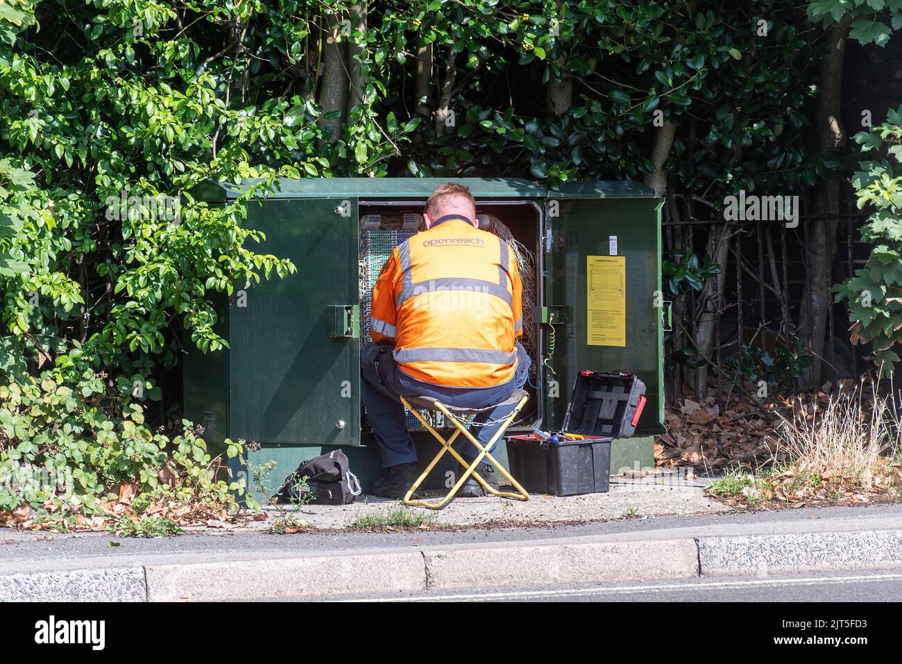 Ingegnere Openreach che lavora in una scatola verde con cavi di comunicazione, mantenendo la rete telefonica e a banda larga, Regno Unito Foto Stock