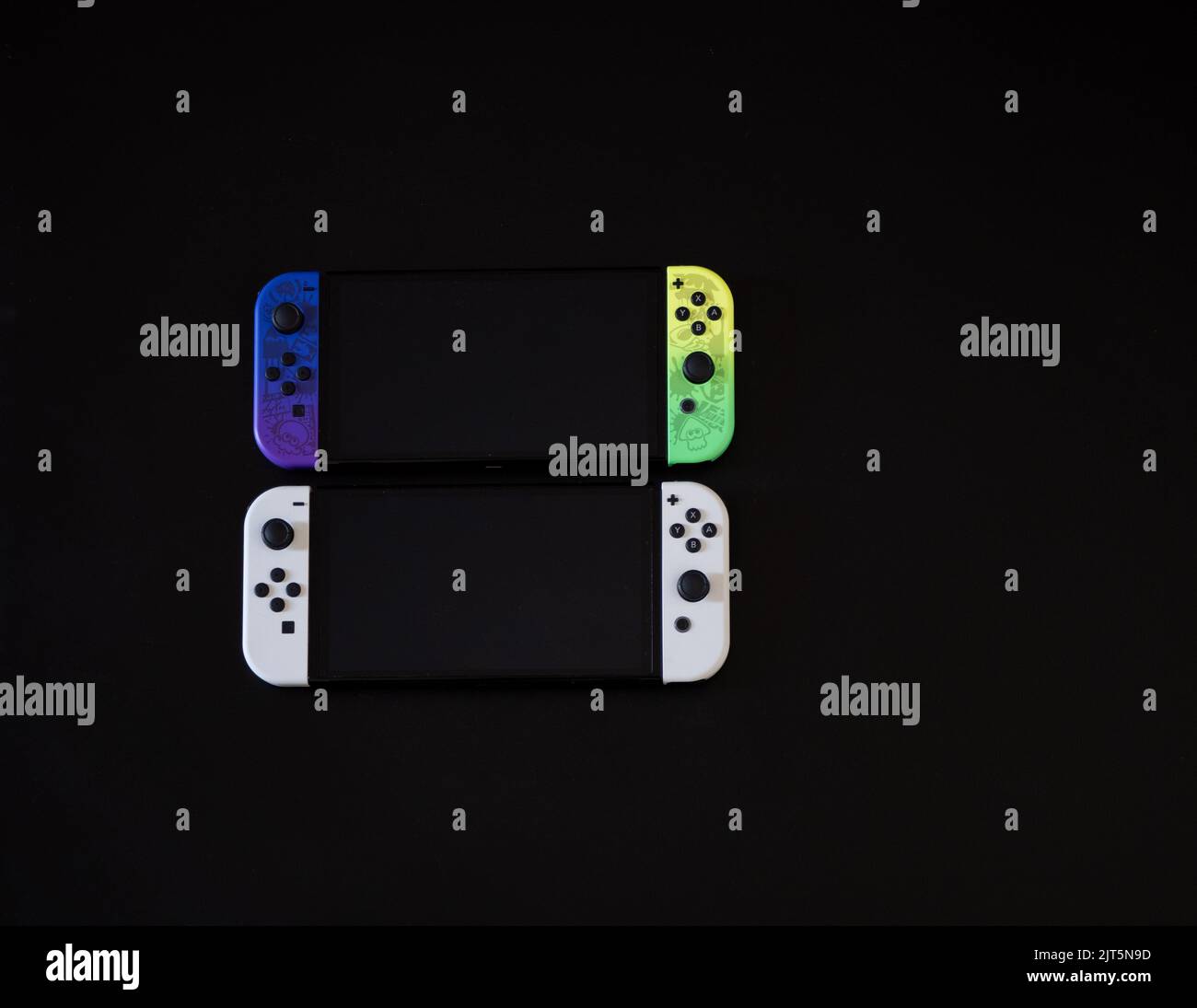 Nintendo Switch Splatoon Special Edition con White OLED Edition su sfondo nero confronto affiancato Foto Stock