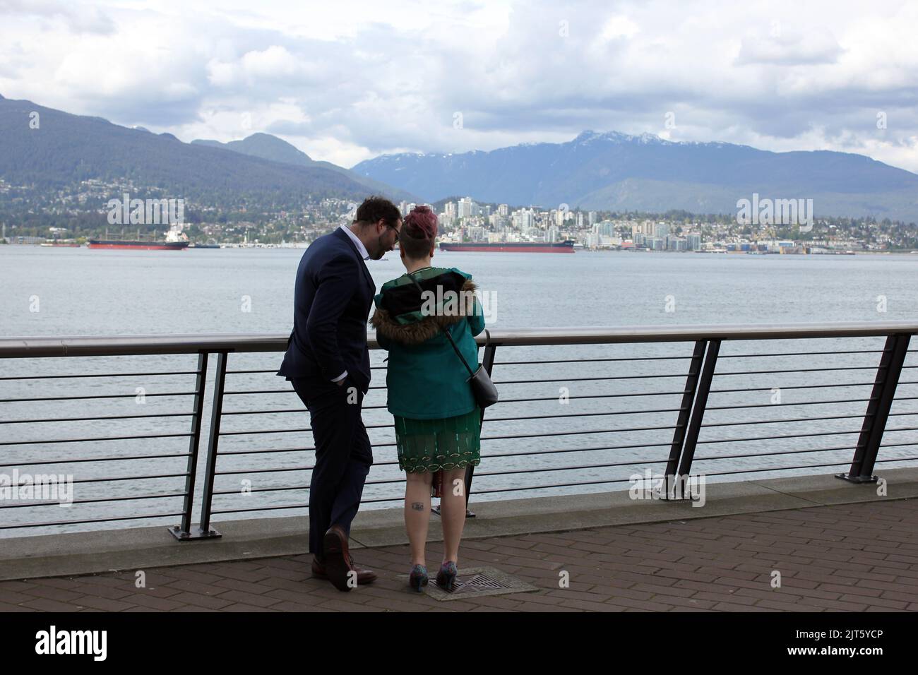 Una giovane coppia che guarda le foto al telefono sul lungomare nel centro di Vancouver, British Columbia, Canada Foto Stock