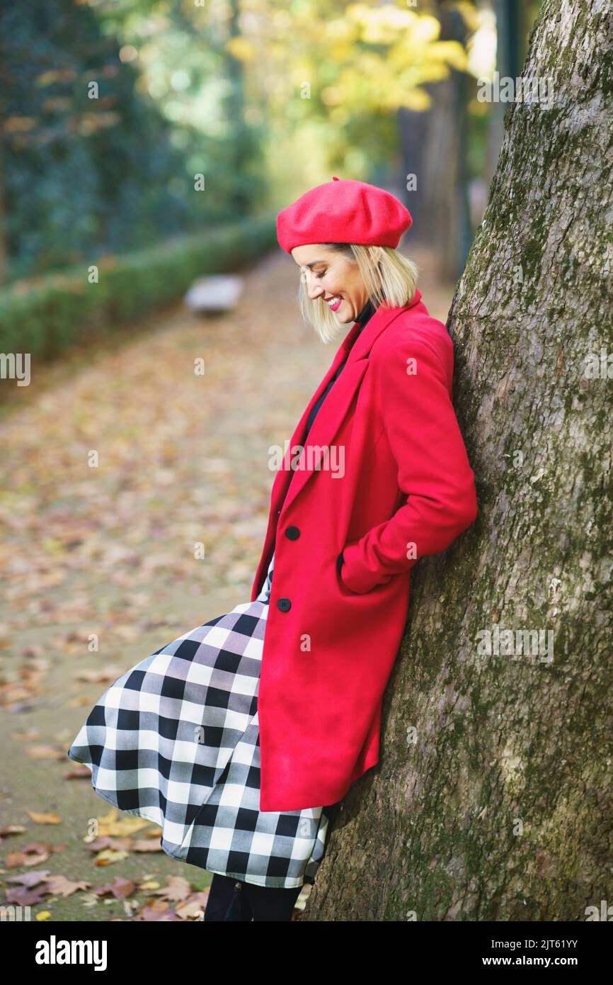 Donna sorridente in piedi vicino all'albero nel parco Foto Stock