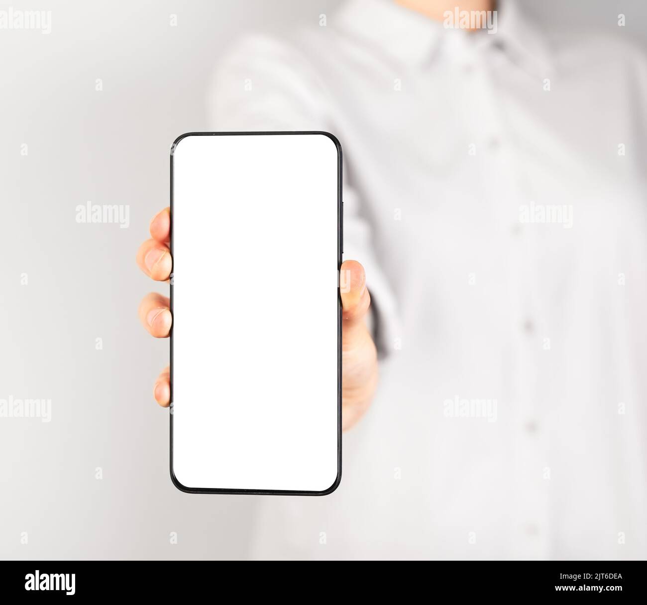 Donna che tiene il mockup del telefono in posizione verticale. Donna che utilizza lo smartphone per mostrare foto o informazioni. Modello telefonico con display vuoto. Alto Foto Stock