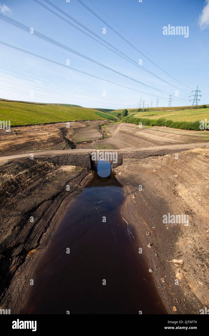 Ripponden, West Yorkshire, UK, 28th agosto 2022 UK Weather Baitings Dam è al suo livello più basso nella memoria recente. Il bacino idrico dello Yorkshire vicino a Ripponden è così asciutto che l'antico ponte a cavallo è stato esposto - sommerso da quando il bacino fu inondato negli anni '1950s - e il letto di quello che un tempo era un lago ora assomiglia ad un paesaggio desertico. Baitings è diventato un'attrazione turistica nelle ultime settimane, poiché i livelli nazionali delle acque nei serbatoi sono scesi al loro livello più basso dal 1995. Credit: Windmill Images/Alamy Live News Foto Stock