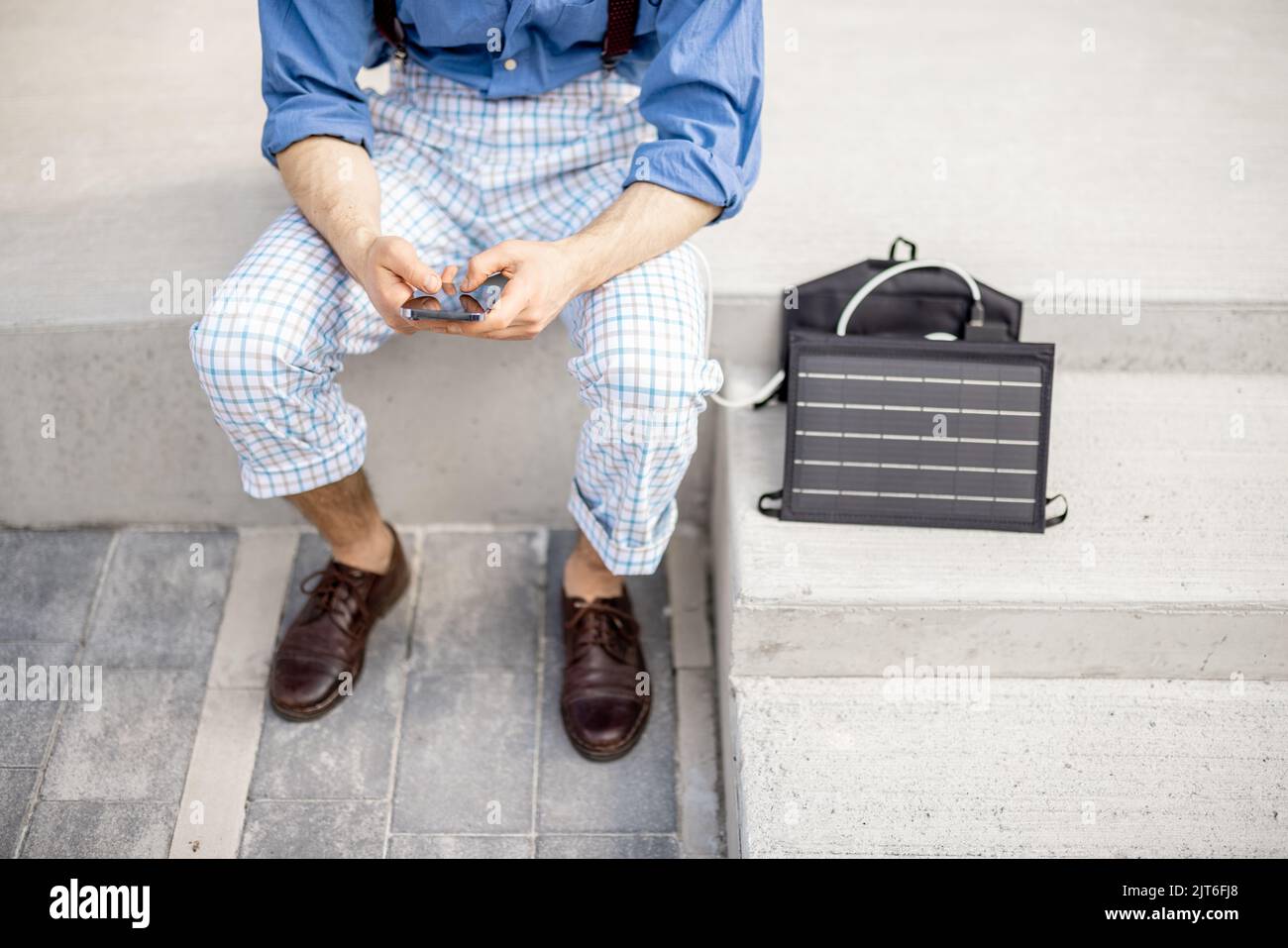 Uomo carica il telefono dal pannello solare portatile Foto Stock