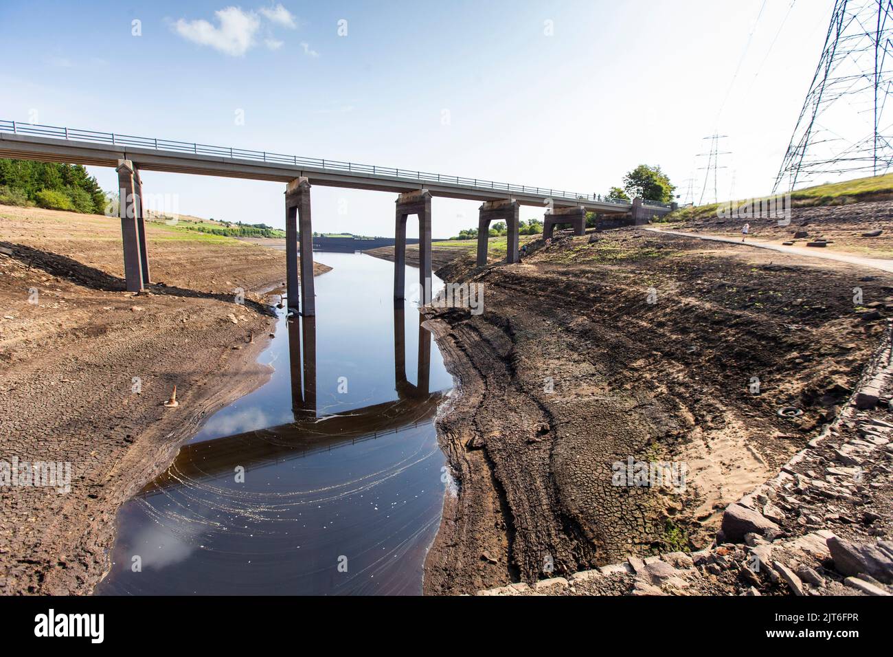 Ripponden, West Yorkshire, UK, 28th agosto 2022 UK Weather Baitings Dam è al suo livello più basso nella memoria recente. Il bacino idrico dello Yorkshire vicino a Ripponden è così asciutto che l'antico ponte a cavallo è stato esposto - sommerso da quando il bacino fu inondato negli anni '1950s - e il letto di quello che un tempo era un lago ora assomiglia ad un paesaggio desertico. Baitings è diventato un'attrazione turistica nelle ultime settimane, poiché i livelli nazionali delle acque nei serbatoi sono scesi al loro livello più basso dal 1995. Credit: Windmill Images/Alamy Live News Foto Stock