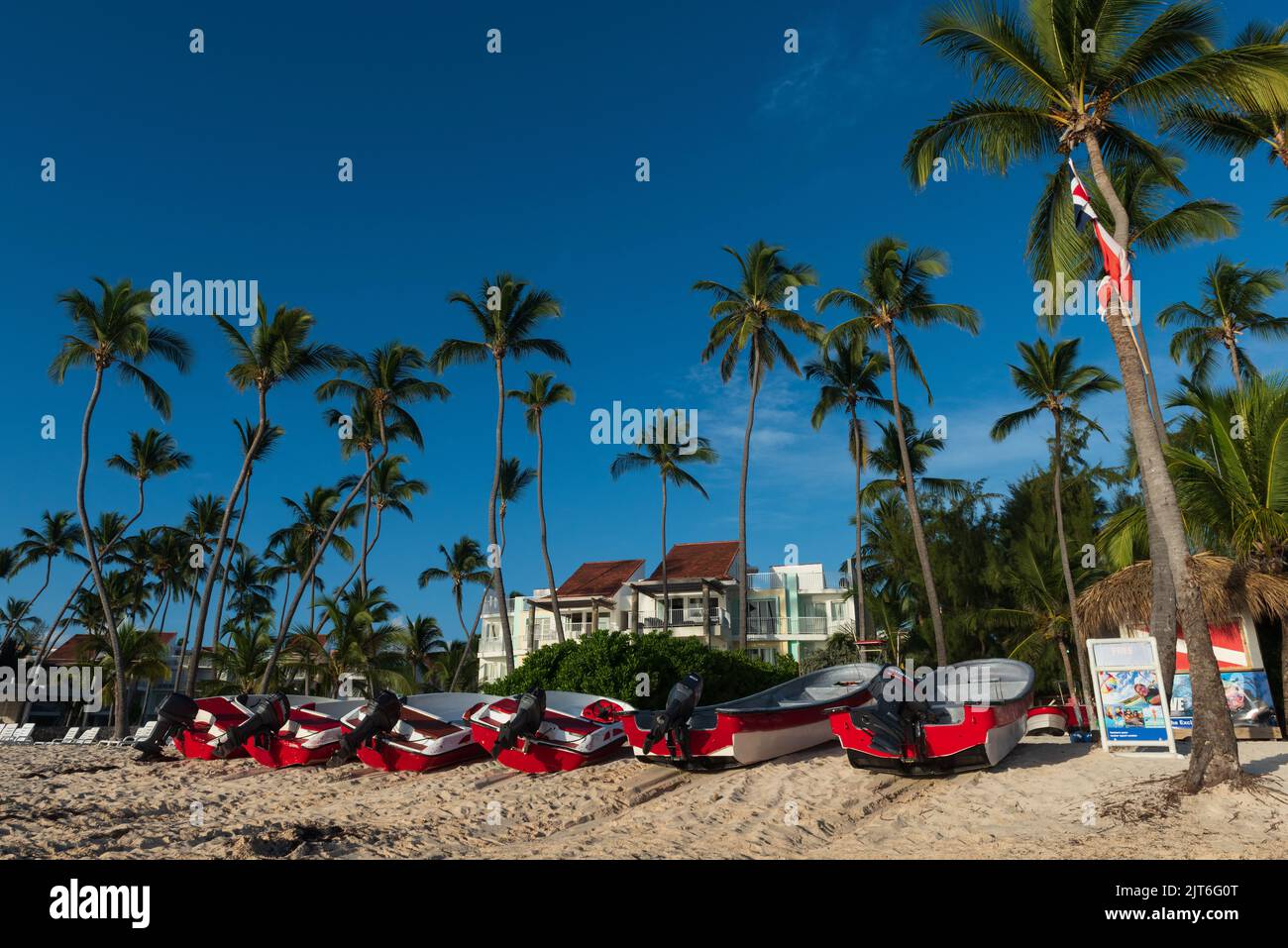 Barche rosse e bianche e palme su Playa Bavaro a Punta Cana nella Repubblica Dominicana. Foto Stock