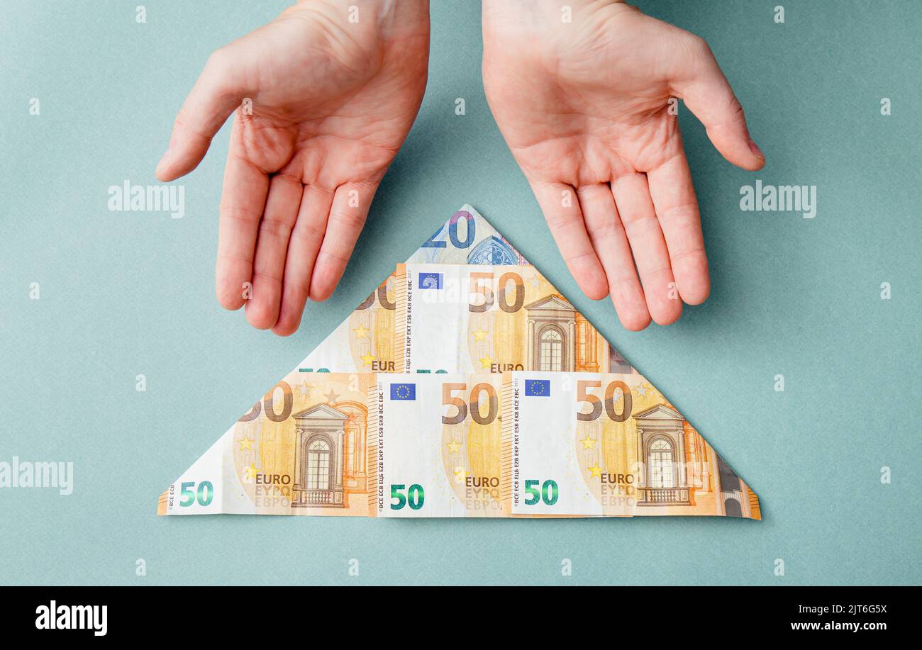 Schema piramidale o concetto di schema Ponzi. Euro denaro piegato a forma di piramide e l'uomo che mostra su sfondo blu, studio shot. Foto Stock