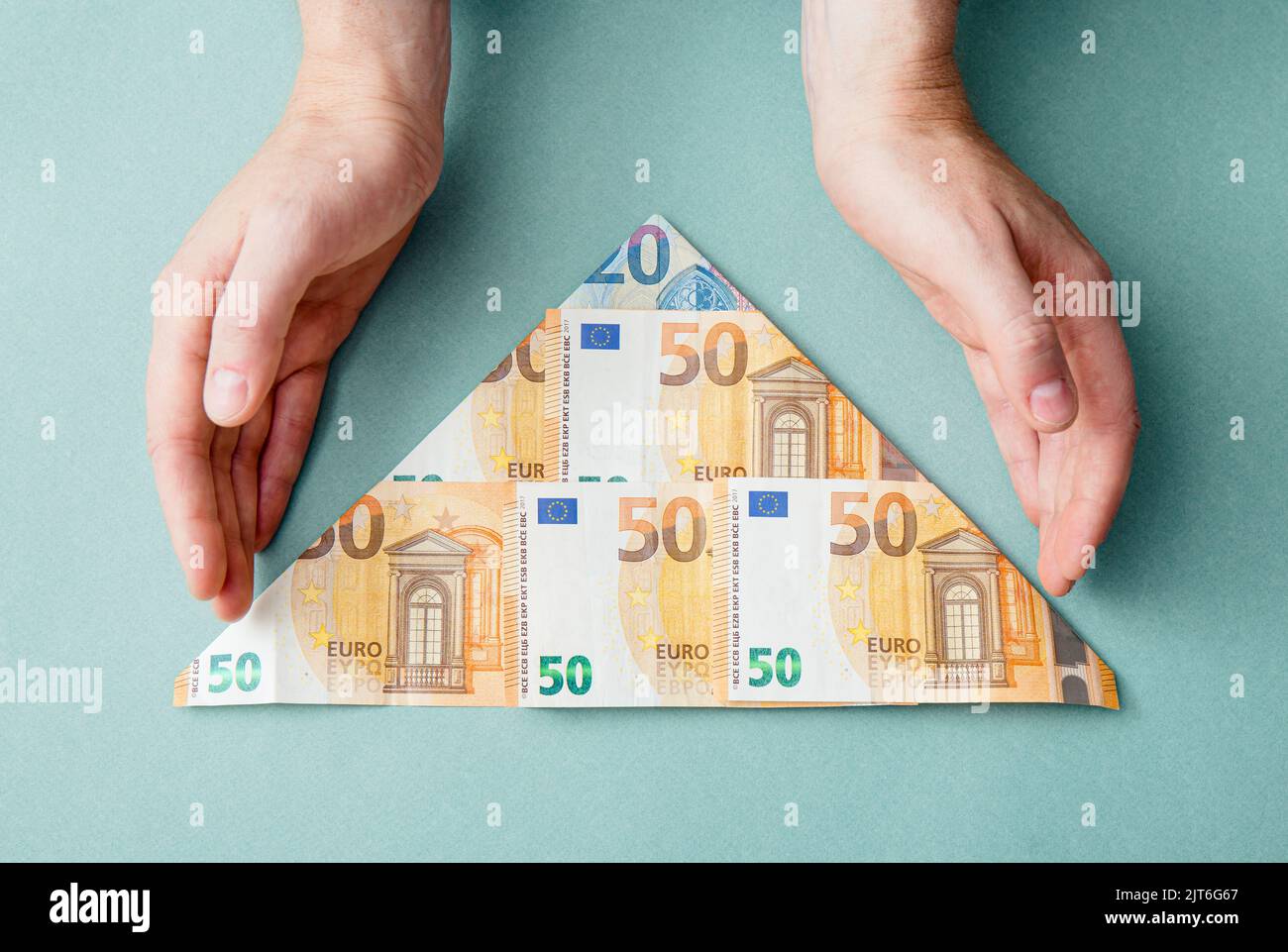 Schema piramidale o concetto di schema Ponzi. Euro denaro piegato a forma di piramide e l'uomo che mostra su sfondo blu, studio shot. Foto Stock