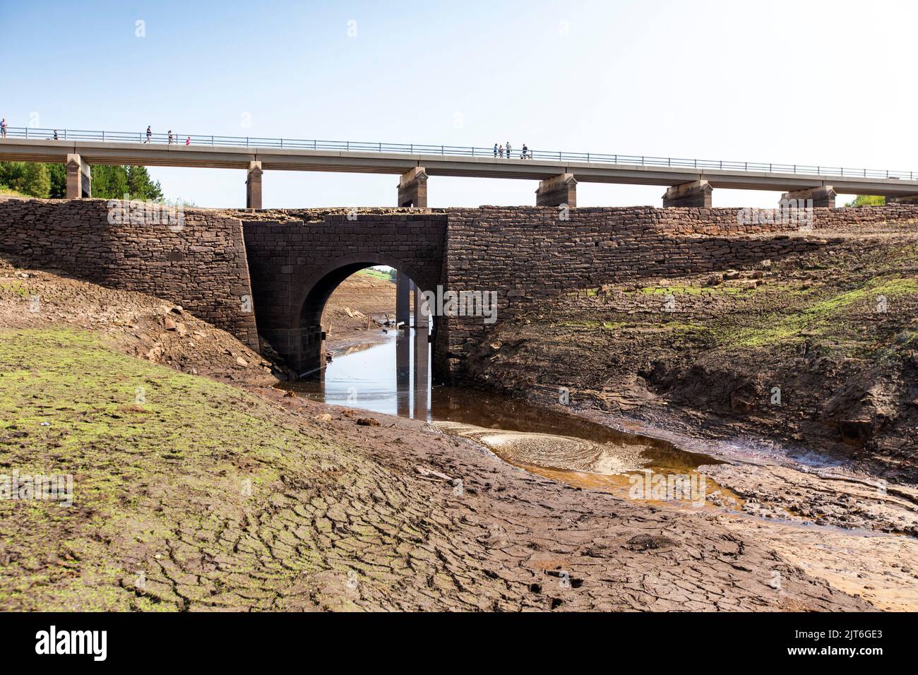 Ripponden, West Yorkshire, UK, 28th agosto 2022 UK Weather Baitings Dam è al suo livello più basso nella memoria recente. Il bacino idrico dello Yorkshire vicino a Ripponden è così asciutto che l'antico ponte a cavallo è stato esposto - sommerso da quando il bacino fu inondato negli anni '1950s - e il letto di quello che un tempo era un lago ora assomiglia ad un paesaggio desertico. Baitings è diventato un'attrazione turistica nelle ultime settimane, poiché i livelli nazionali delle acque nei serbatoi sono scesi al loro livello più basso dal 1995. Credit: Windmill Images/Alamy Live News Foto Stock