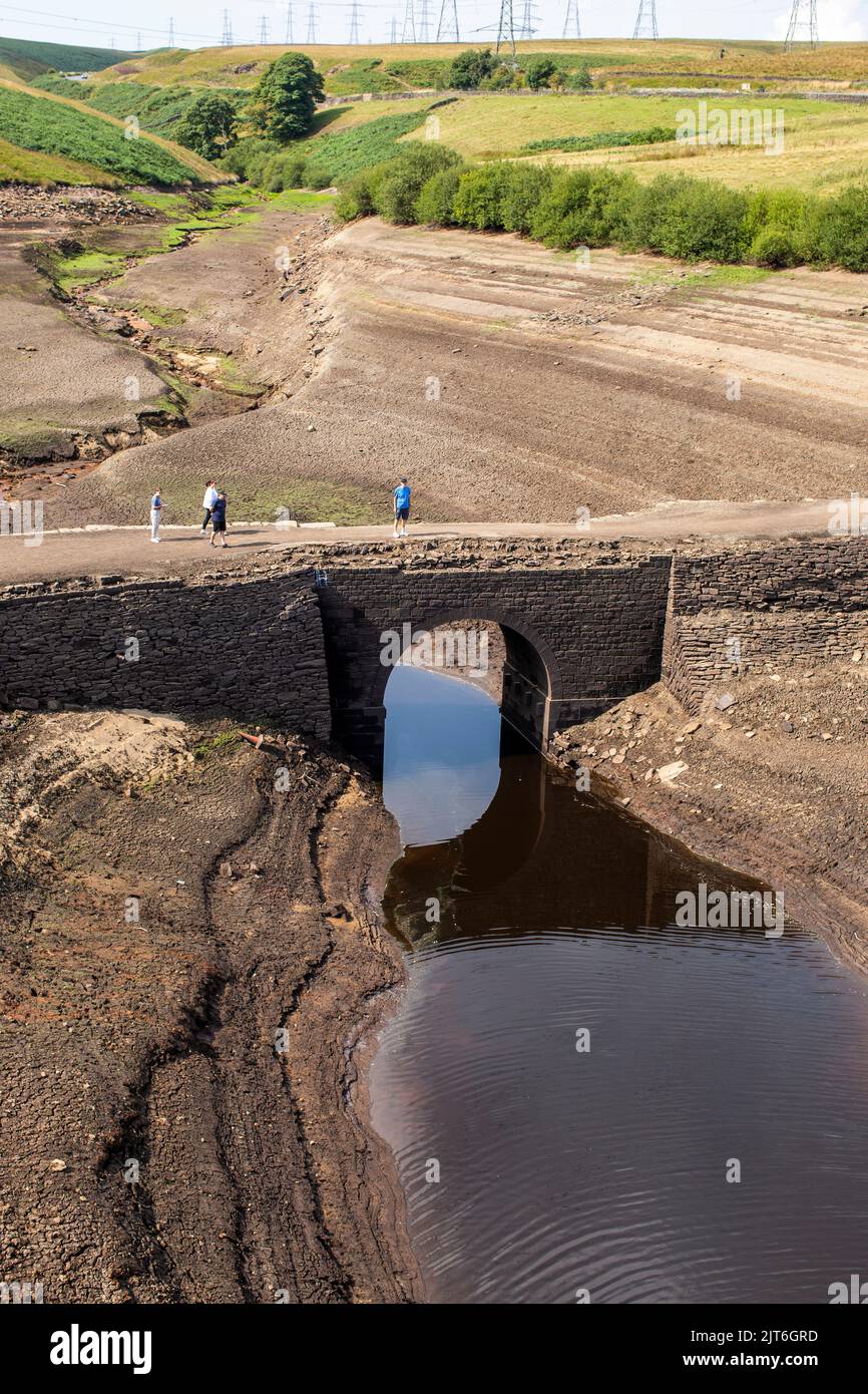 Ripponden, West Yorkshire, UK, 28th agosto 2022 UK Weather Baitings Dam è al suo livello più basso nella memoria recente. Il bacino idrico dello Yorkshire vicino a Ripponden è così asciutto che l'antico ponte a cavallo è stato esposto - sommerso da quando il bacino fu inondato negli anni '1950s - e il letto di quello che un tempo era un lago ora assomiglia ad un paesaggio desertico. Baitings è diventato un'attrazione turistica nelle ultime settimane, poiché i livelli nazionali delle acque nei serbatoi sono scesi al loro livello più basso dal 1995. Credit: Windmill Images/Alamy Live News Foto Stock