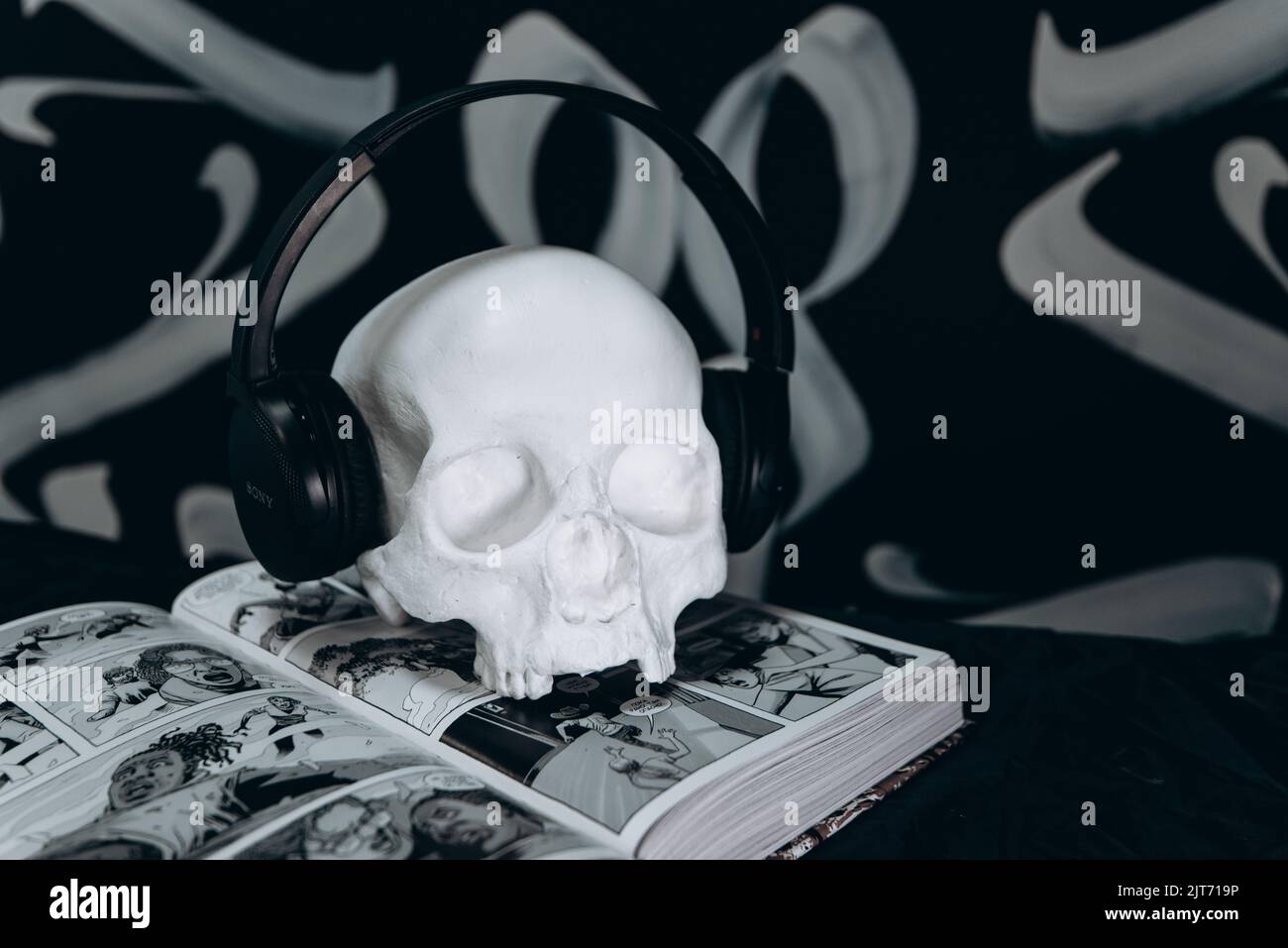 un cranio in gesso bianco che indossa le cuffie su uno sfondo bianco e nero del fumetto. tema di halloween. Foto Stock