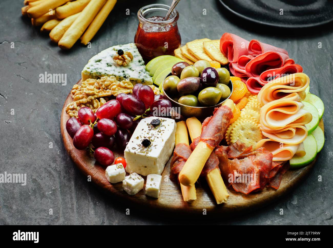 Il piatto di formaggi perfetto con varietà di deliziosi frutti freschi, marmellata, noci, cracker, burro e formaggio liscio e frutta secca. Foto Stock