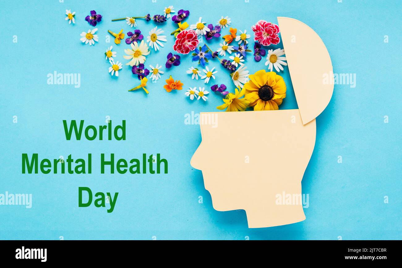 Concetto di giornata mondiale della salute mentale. Simbolo della testa umana e fiori su sfondo blu Foto Stock