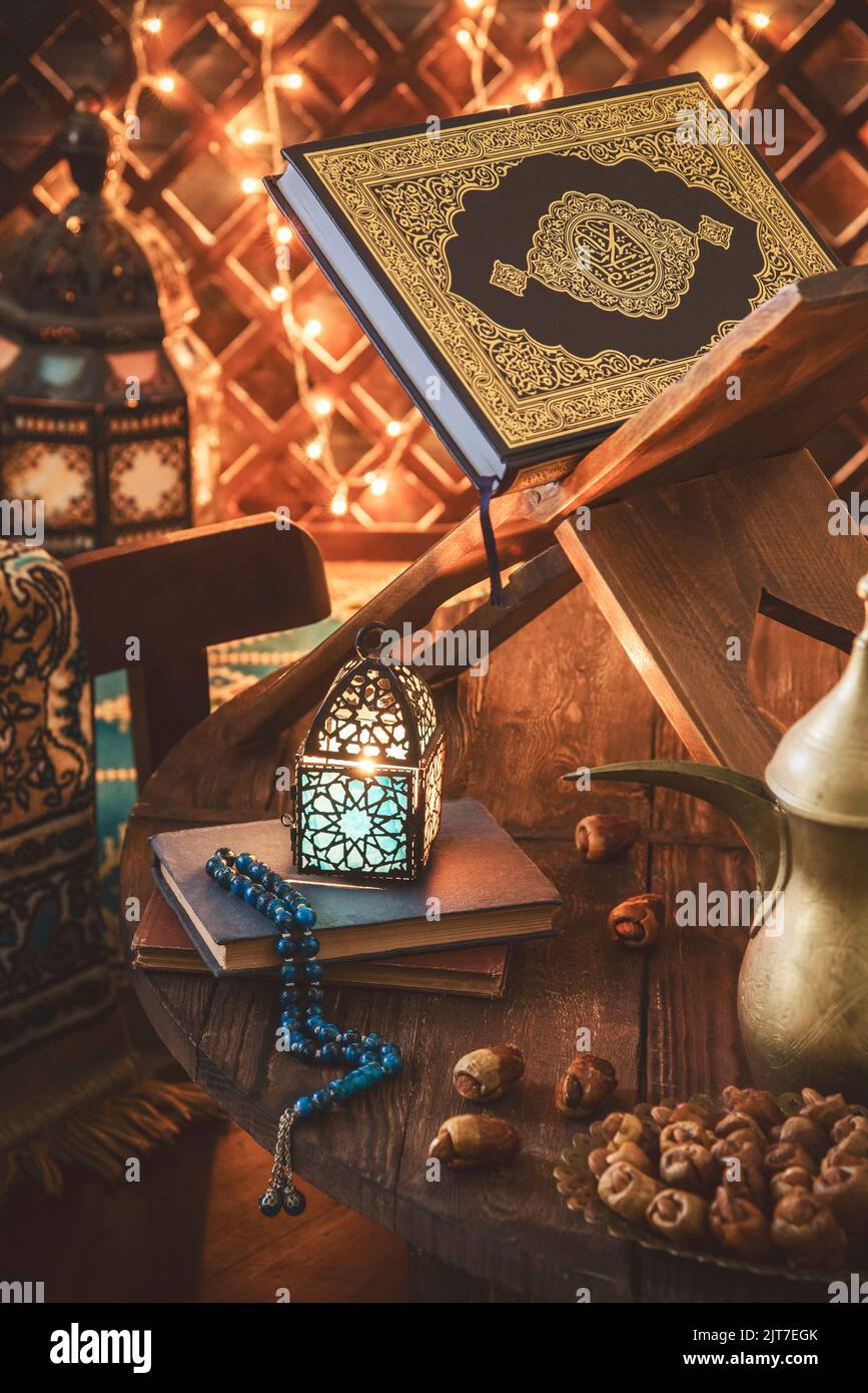 Sfondo Ramadan; primo piano per il Santo 'Corano' posto con lampada Ramadan illuminata, datteri freschi, tappeto di preghiera e perle di rosario. Foto Stock